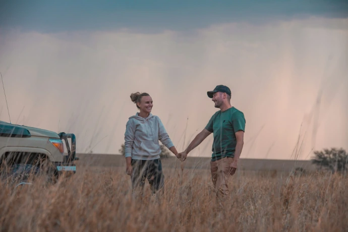 a man and a woman holding hands in a field