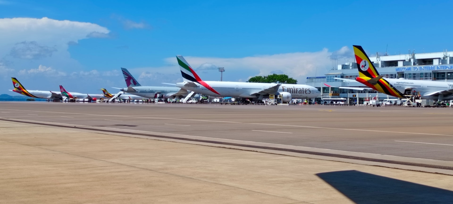 A view of Entebbe International Airport in Uganda A row of parked airplanes sitting on top of an airport tarmac